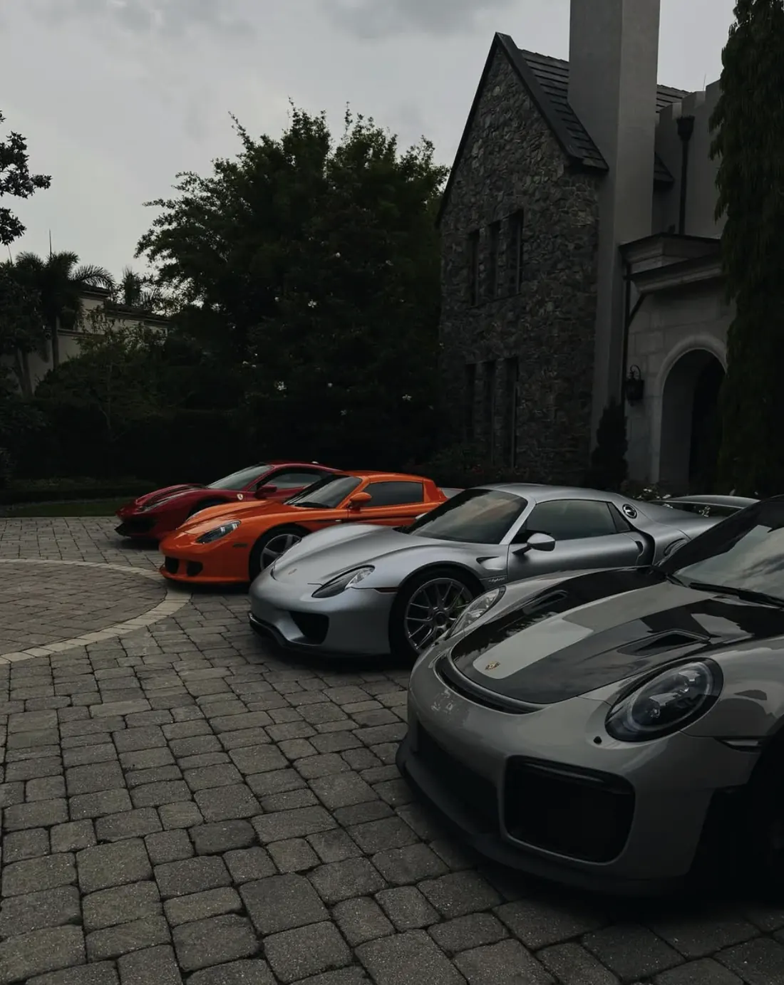 Four supercars lined up on a stone driveway